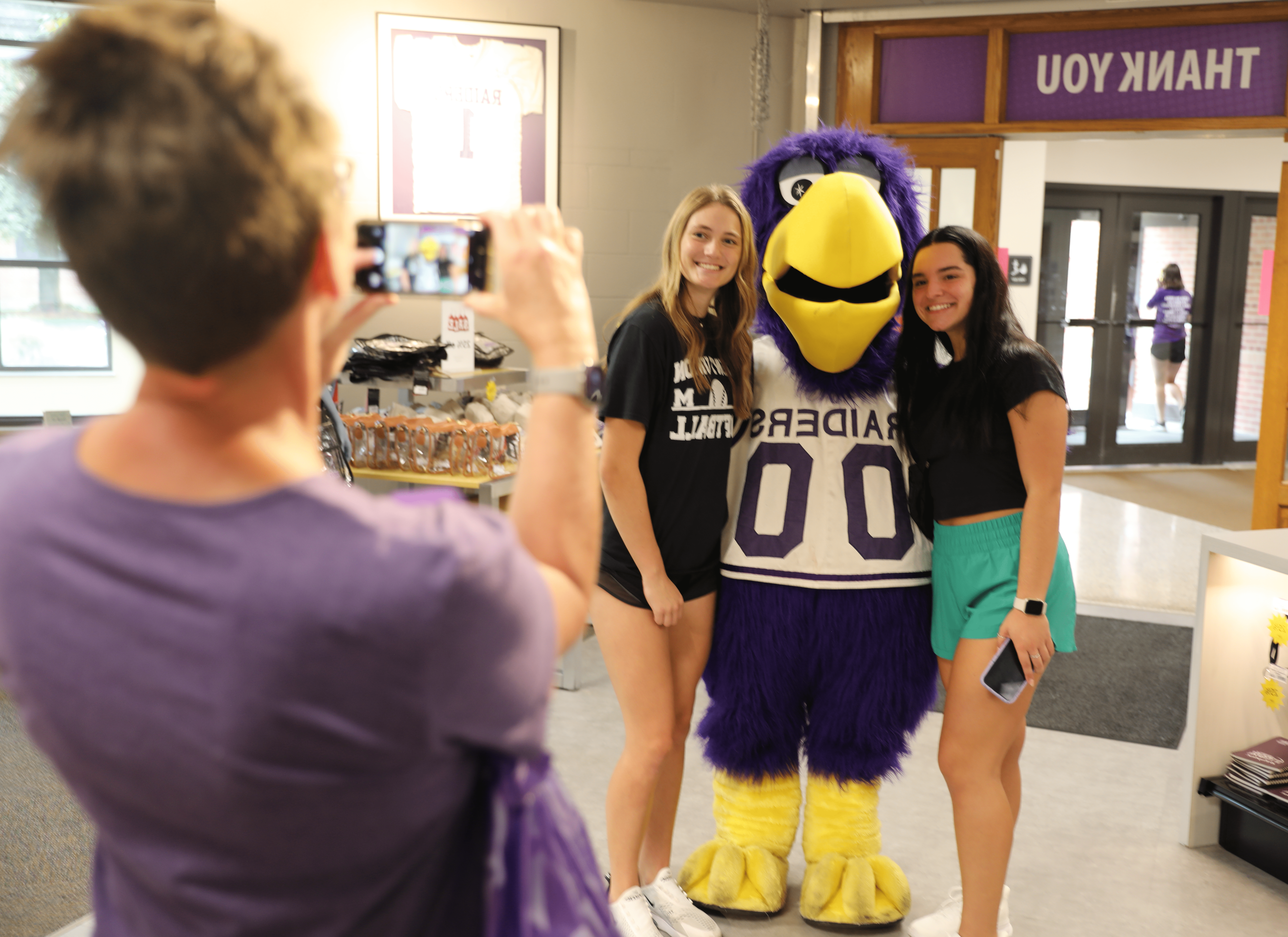 students taking photo with mascot